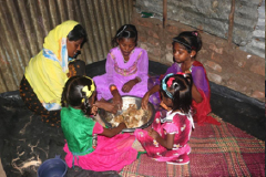 children sit to eat with their mother in a shelter