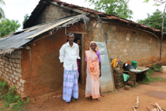 two old people standing in front of their shelter